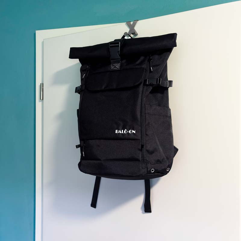 Schwarzer BALÔ-one Rucksack hängt an einem Haken an der Tür – ein praktisches Beispiel für die platzsparende und griffbereite Aufbewahrung eines Rucksacks im Alltag