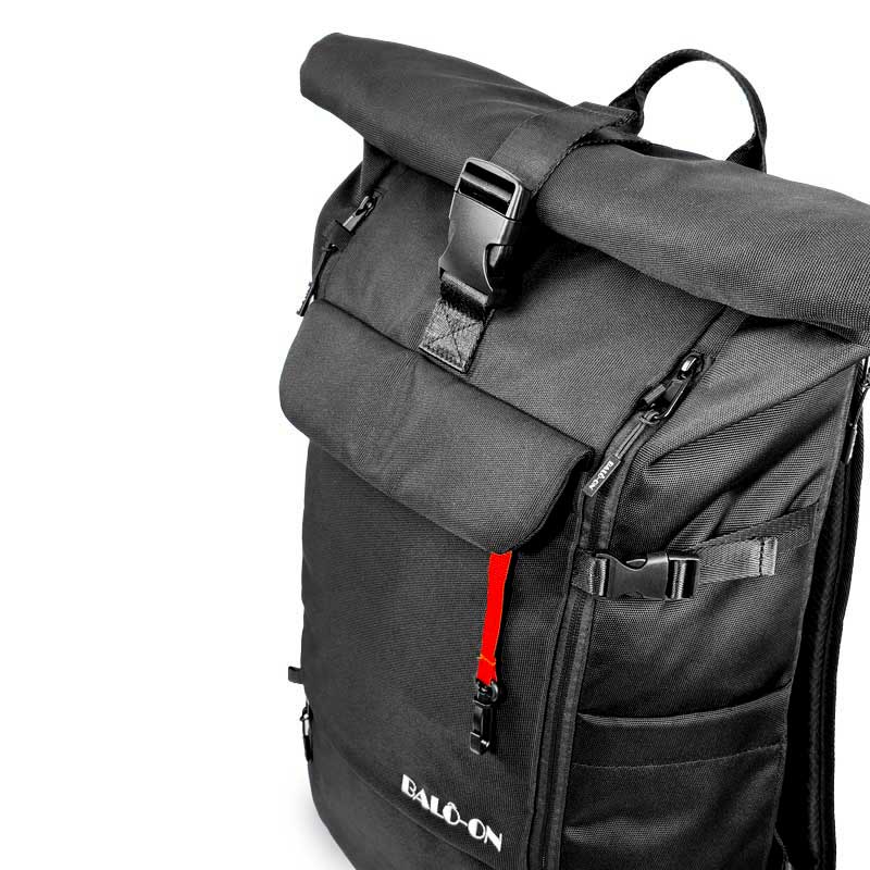Nahaufnahme des schwarzen Rucksacks, bei der die Gurte aus strapazierfähigem Gurtbandmaterial gut sichtbar sind. In der Vordertasche ist ein roter Schlüsselanhänger zu erkennen.
