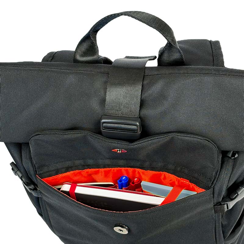 Schwarzer Rolltoprucksack der Marke BALÔ-ON, Ansicht von oben; geöffnete Fronttasche mit Magnetverschluss und Schlüsselanhänger, gefüllt mit Stiften und Notizbuch.
