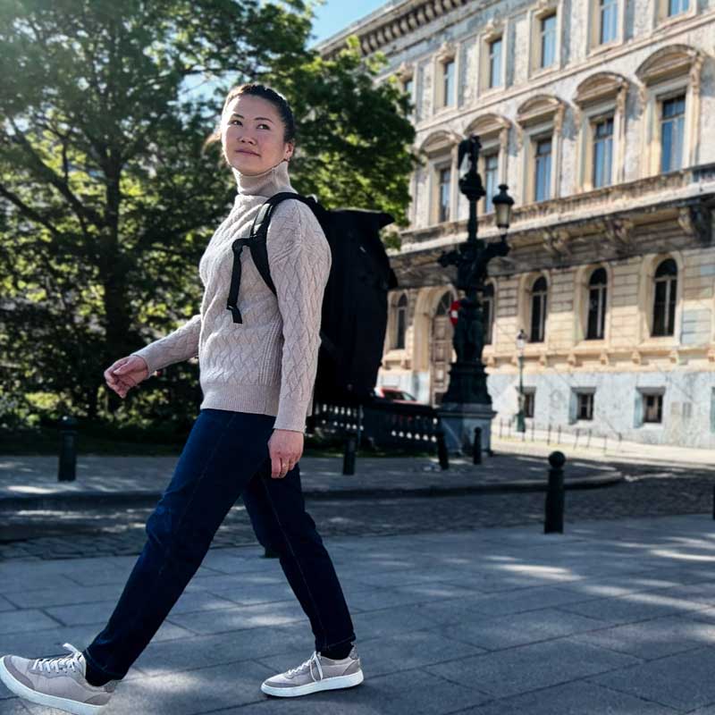 Junge Frau mit Rucksack läuft durch die Altstadt von Brüssel, umgeben von historischen Gebäuden.