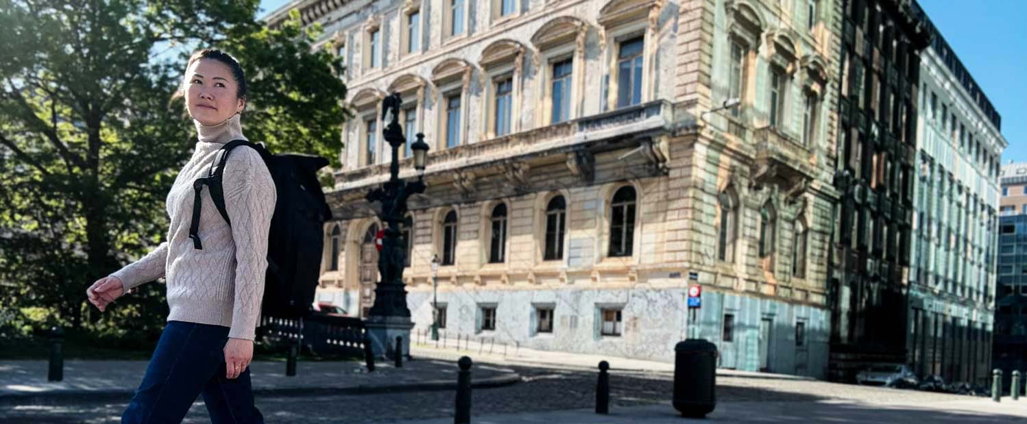 Junge Frau trägt einen schwarzen Rucksack von BALÔ-ON und läuft durch eine Altstadt.