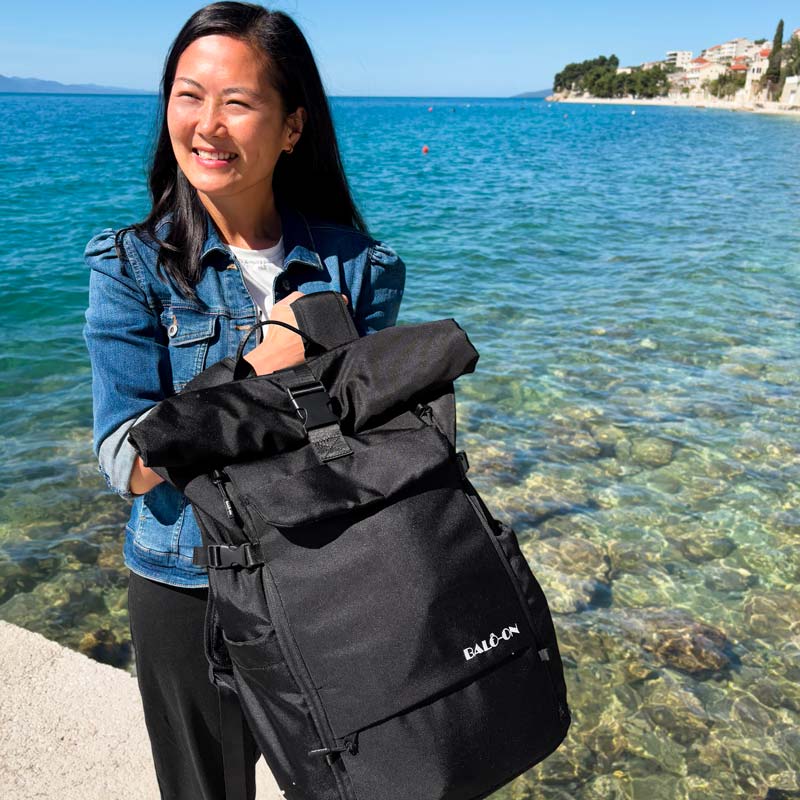 Junge Frau präsentiert den schwarzen BALÔ-one Black 25 Liter Rucksack.