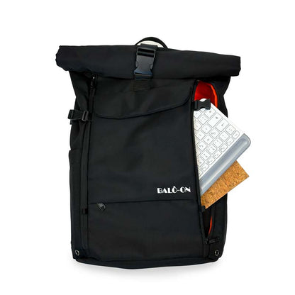 Schwarzer Rolltoprucksack der Marke BALÔ-ON, Vorderansicht, stehend auf weißem Hintergrund; schneller Zugriff auf das Hauptfach durch Reißverschluss, im Hauptfach sind eine Tastatur und ein Notizbuch zu sehen: