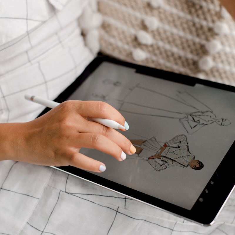 Gepflegte Hand einer jungen Frau hält einen Stift für ein Tablet und designt Mode.